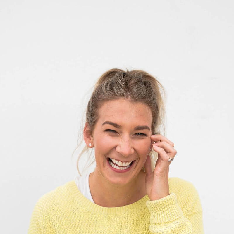 Lou Fitz from BESHU laughing in a yellow jumper against a white wall