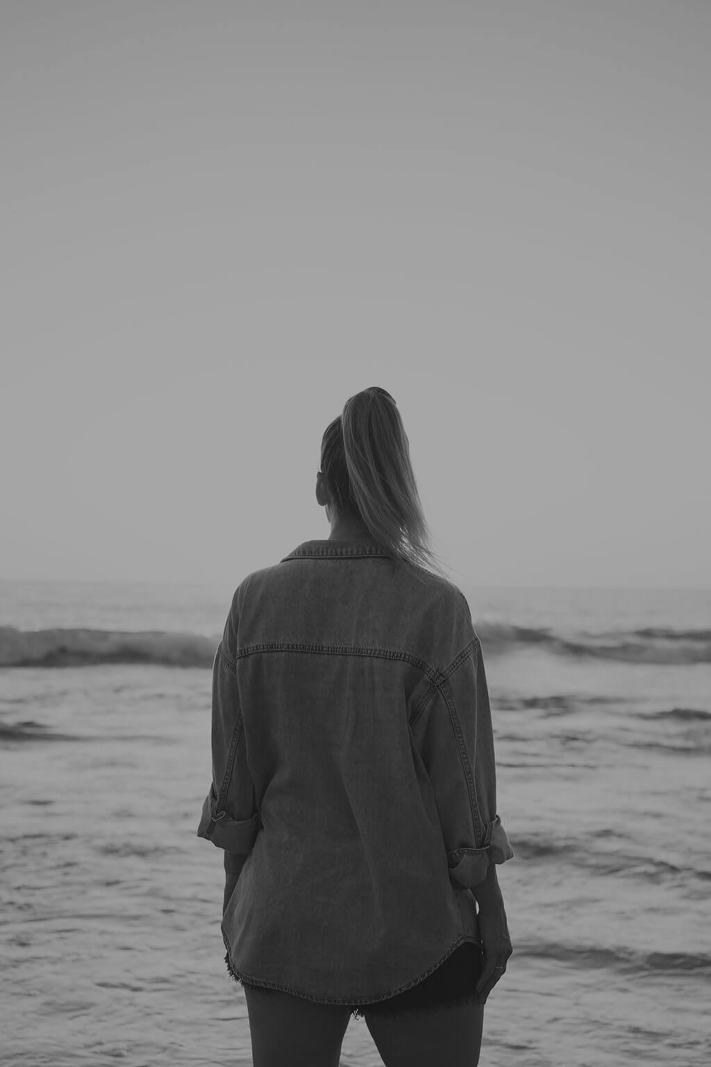 Black and white photo of Lou Fitz standing alone, facing the sea